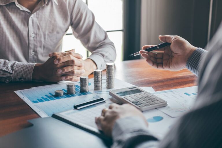 Pessoas analisando documentos e gráficos em uma mesa de trabalho